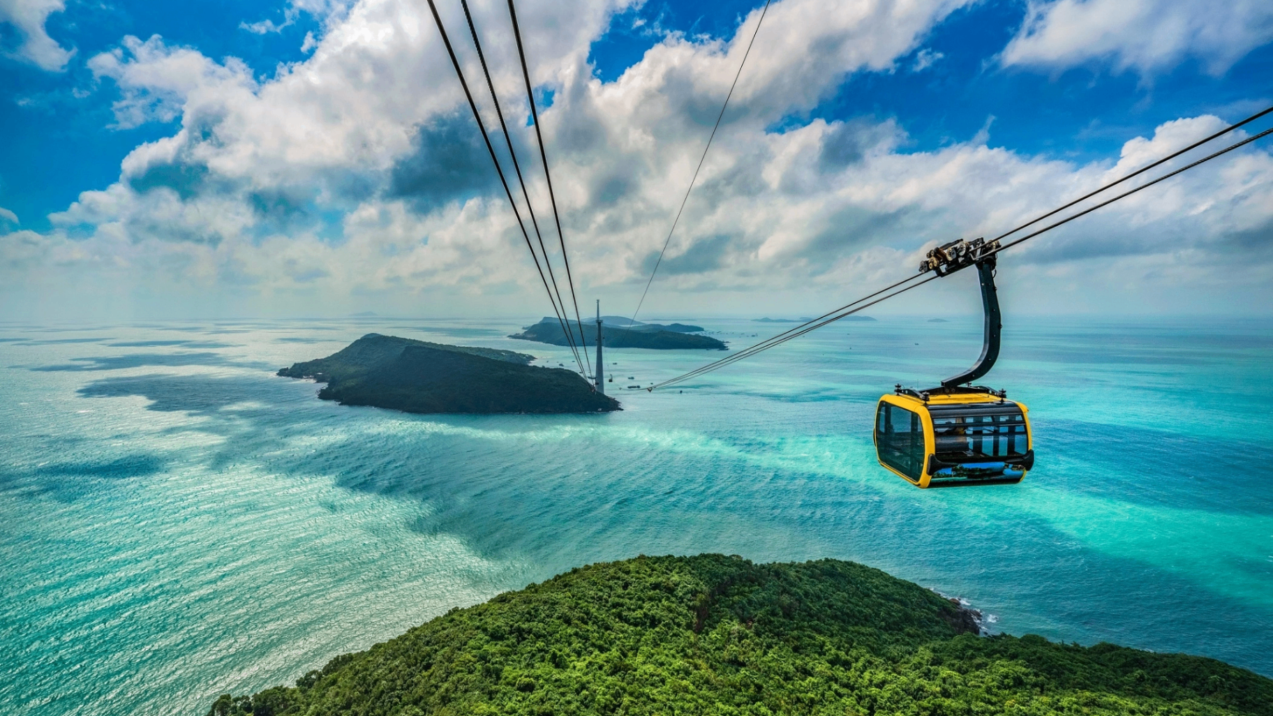 Yellow cable car floating over islands and sea in Phu Quoc.