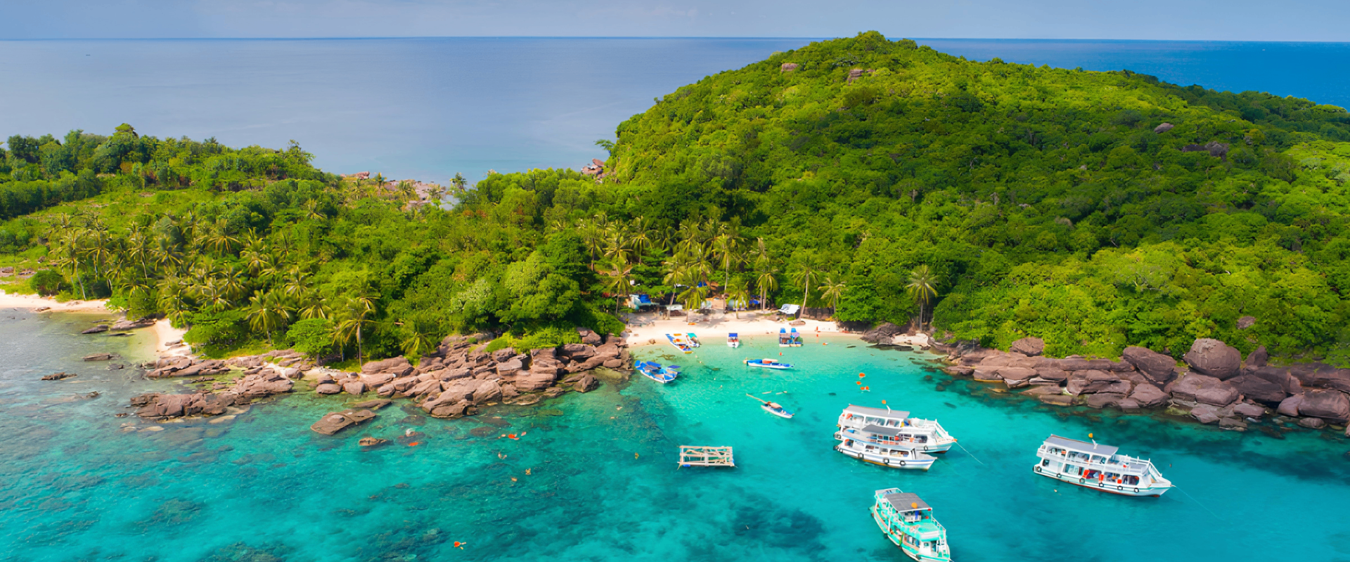 Phu Quoc turquoise water, boats, and lush island shore.