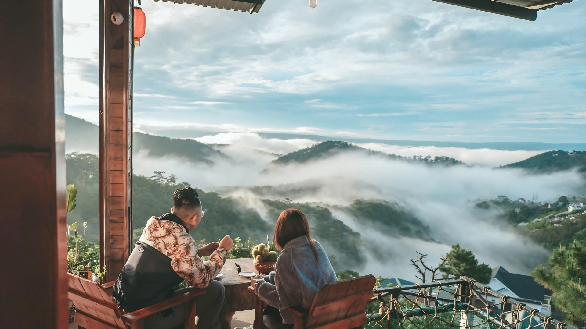Couple enjoying breakfast with misty Da Lat hills beyond.