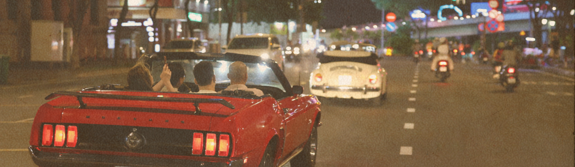 Retro convertible cruising through Saigon at night.