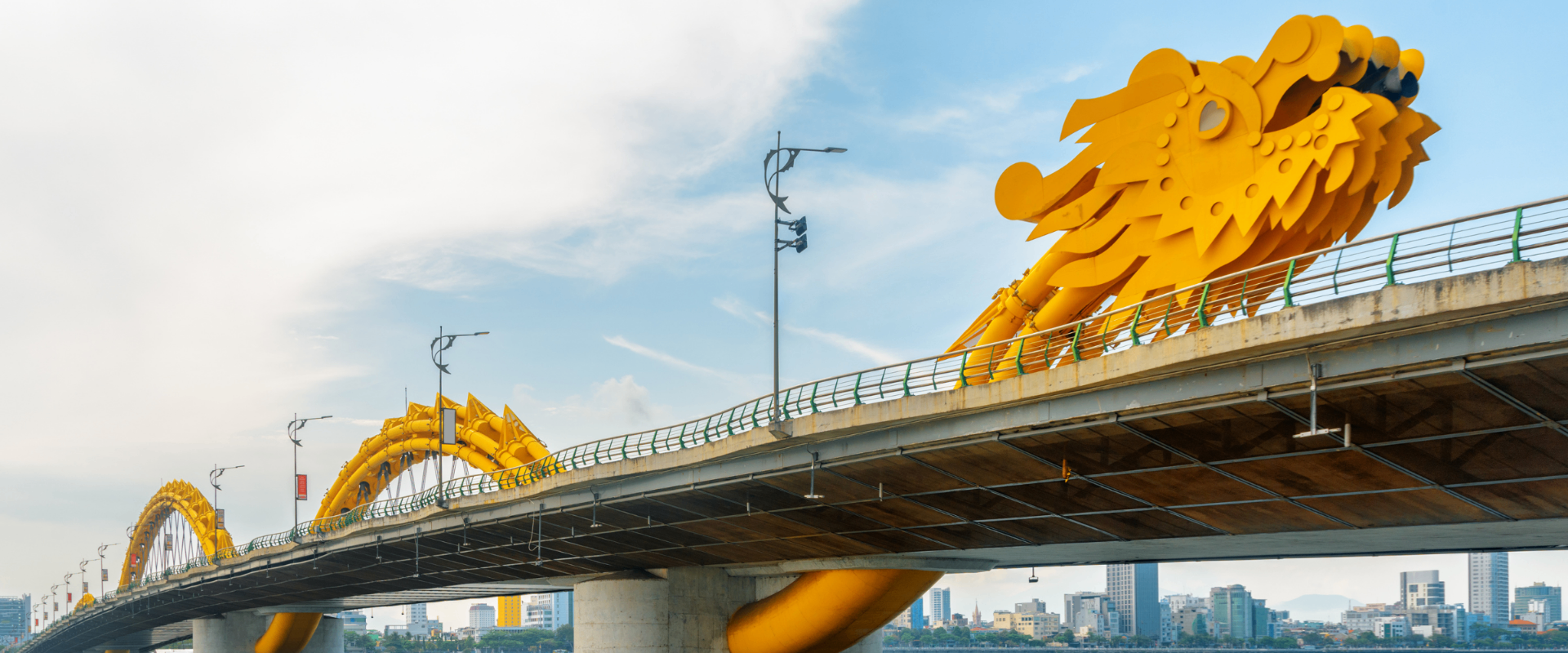 Golden Dragon Bridge stretching across Da Nang under a bright sky.